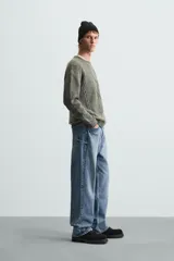 Sweater verde oliva de punto con cuello redondo, manga larga y diseño de trenzas en el frente.