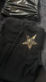 Pantalón negro de tiro bajo y corte ancho, con apliques de estrellas de animal print en la parte trasera.