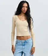 Suéter de punto color beige, con escote en V y mangas largas.