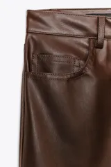 Pantalón negro de tiro medio, con trabillas en la cintura, cinco bolsillos y pernera ancha. Cierre frontal con cremallera, botón oculto y gancho metálico.