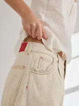 Bermuda color marrón claro, de tiro medio/alto, calce cómodo y relajado, con detalle de voladito en bolsillos.