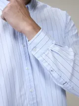 Camisa celeste a rayas verticales, de manga larga y corte clásico.