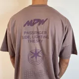 Remera lila con estampado en la espalda que incluye texto, un logo y un diseño geométrico.