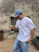 Remera blanca de algodón con corte boxy y parche bordado con la palabra "Brokers" en óvalo azul y verde.