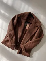 Campera gamulán marrón con interior de piel sintética, corte oversize, cierre frontal con cremallera y cuello con solapas amplias.