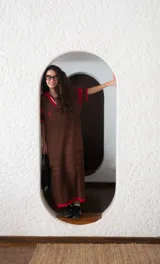 Remerón tejido color marrón con calados y cuello estilo camisa con detalles en rojo.