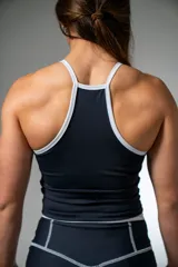 Musculosa deportiva de lycra negra con cuello halter y ribetes blancos.