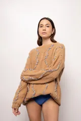 Sweater tejido a mano con lana merino color beige, con bordados verticales en hilo celeste.