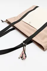 Bolso tipo tote de nylon color negro con bolsillo frontal blanco y asas largas color beige.