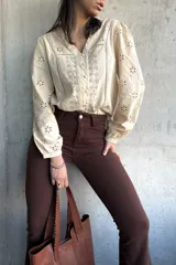 Camisa color manteca con bordado inglés, cuello en V y mangas largas abullonadas.
