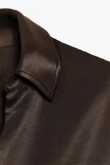 Camisa de mujer satinada color blanco, confeccionada en hilatura con viscosa. Tiene cuello solapa, manga larga con puños y cierre frontal con botones.
