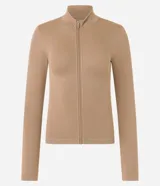 Campera deportiva color beige, de corte ajustado, confeccionada en tejido de poliamida seamless con textura acanalada y cuello alto. Posee cierre delantero por cremallera y mangas largas.