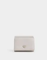 Billetera pequeña de cuerina color blanco hueso, con broche de corazón metálico y botón a presión.