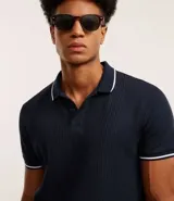 Chomba polo blanca de viscosa texturizada a rayas, corte regular, con cuello y mangas cortas en ribana con detalle contrastante en negro.