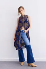 Camisa larga sin mangas confeccionada en viscosa azul con estampado de flores doradas y cuello mao. Presenta bordados en cuello y cartera frontal, y cierre frontal con cremallera.