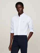 Camisa celeste de corte slim fit con microestampado, cuello abotonado, mangas largas con puños redondeados y logo de Tommy Hilfiger bordado en el pecho.
