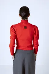Polera roja de tejido de punto con cuello alto y mangas largas abullonadas en los hombros.
