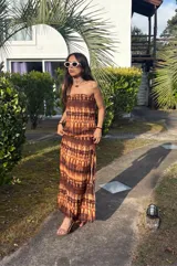 Vestido strapless largo con estampado batik en tonos marrones y ocre, corte ajustado al cuerpo y espalda descubierta.