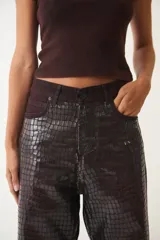 Pantalón de jean de corte ancho con estampado de piel de cocodrilo color bordó.