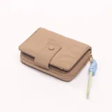 Billetera pequeña color camel con cierre de botón a presión y cierre de cremallera. Incluye llavero decorativo con cordones celeste y amarillo.