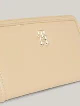 Billetera estilizada grande color beige, con cierre a presión y múltiples compartimentos para billetes y tarjetas, destacándose la insignia del monograma TH.