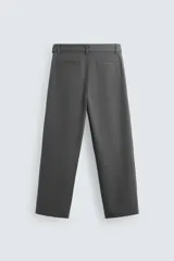 Pantalón negro de corte amplio con cinturón de tela con hebilla metálica. Presenta pliegues frontales, bolsillos laterales y traseros. Cierre frontal con cremallera y botón.