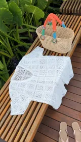 Vestido playero blanco de tejido calado tipo encaje de algodón, corte recto y suelto, con mangas cortas, escote en V y botonadura frontal.