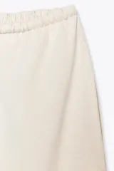 Pantalón ancho color beige, de tiro medio y cintura ajustable con cordones.