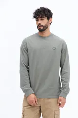 Remera de manga larga color negro, con escote redondo y un pequeño logo circular estampado en el pecho.