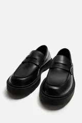 Mocasín de cuero color marrón oscuro, con antifaz y suela track de goma negra.