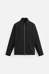 Sobrecamisa color crema de tejido técnico ligero, corte regular fit, cuello solapa, manga larga con puños abotonados, bajo ajustable con elástico en laterales y cierre frontal con cremallera.