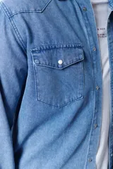 Camisa de manga larga de jean azul claro, con dos bolsillos con solapa abotonada en el pecho.