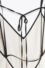 Vestido largo color blanco hueso de satén, con escote en V y tirantes finos negros ajustables en la espalda.