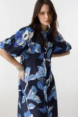 Vestido midi de lino azul marino con estampado floral en tonos celeste y blanco, cuello mao, mangas abullonadas hasta el codo y cierre frontal con botones de nácar.