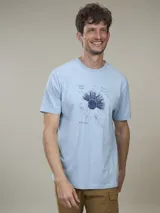 Remera celeste con estampado de un diseño floral en azul y texto en la parte inferior.