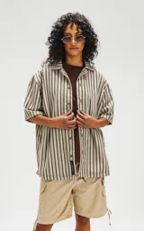 Camisa oversize de manga corta con cuello abierto y estampado a rayas verticales en tonos verde y beige.