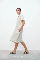 Vestido midi color crudo de lino, corte recto, con cuello en V, mangas cortas y bolsillos laterales.