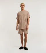 Conjunto de pijama para hombre, compuesto por una remera de manga corta con cuello redondo y un short con cintura elástica y cordón de ajuste. El tejido es de malla flamê con efecto mezcla en tonos beige y marrón.