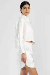 Camisa blanca de lino italiano con hilo metalizado, cuello clásico y botón de flor en el cuello.