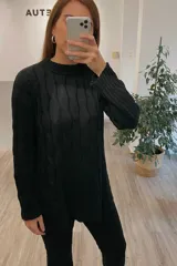 Sweater negro de punto con cuello redondo y diseño trenzado. Corte holgado y largo asimétrico.