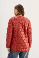 Campera color ladrillo con matelassé de corazones, corte amplio, mangas largas y bolsillos con solapa y botones snap en el frente.