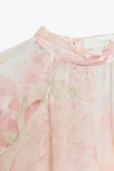 Camisa de cuello subido y manga larga con estampado floral en tonos rosa y verde. Detalle de volantes en cuello, mangas y ruedo. Cierre en espalda con abertura y botones.