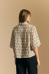 Camisa de manga corta con cuello camisero, confeccionada en tela estampada con diseño paisley en tonos negro, beige y azul.