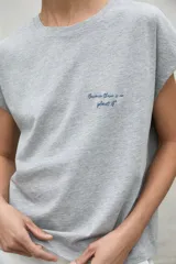 Camiseta gris de manga corta con cuello redondo y texto estampado en el pecho.