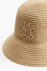 Sombrero tipo bucket de paja color beige con ala corta y logo bordado en el frente.