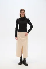 Sweater negro de punto con cuello alto y botones metálicos decorativos en hombros y mangas largas.