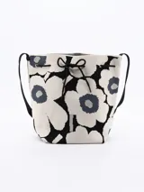 Bandolera tipo bucket con estampado de flores en blanco y negro, cierre con cordón ajustable y correa larga de hombro.