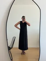 Vestido largo azul marino de tejido acanalado, con escote redondo y mangas cortas tipo hombrera. Presenta una abertura lateral en la falda.