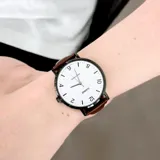 Reloj Casio con caja negra, esfera blanca con números arábigos y correa de cuero marrón.