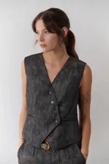 Chaleco grafito con cuello en V, cierre frontal con botones y bolsillos ribeteados.
